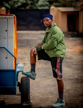 Stylish young man posing with a street cart in an urban setting. Vibrant and dynamic.