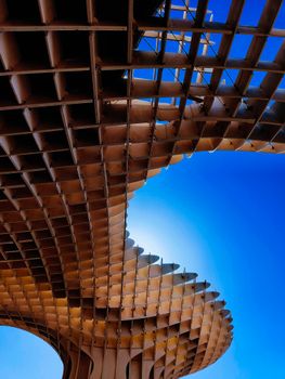 Dynamic perspective of a modern wooden structure under a bright blue sky, showcasing architectural innovation.