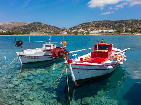 Traditional Greek fishing boats on clear waters in a serene Mediterranean bay, under a bright blue sky.