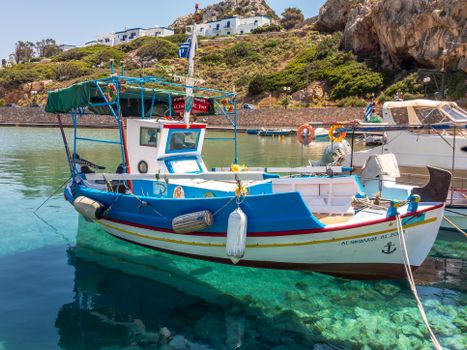 Colorful fishing boat in Syros, Greece. Clear waters under a vibrant blue sky.