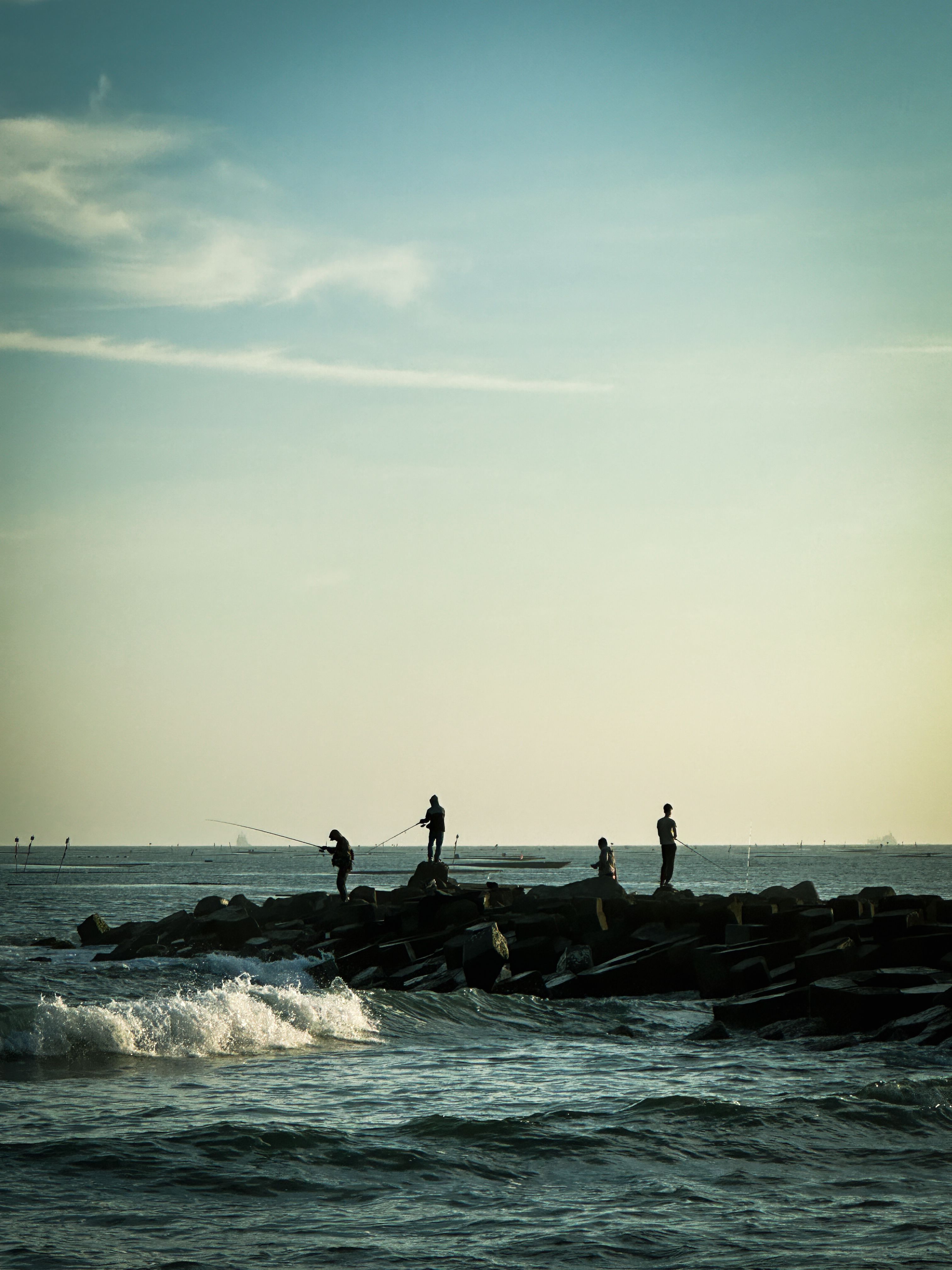 A group of people standing on rocks near the ocean · Free Stock Photo