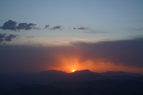 Free A breathtaking sunset over a mountain range with clouds, captured in a serene landscape. Stock Photo