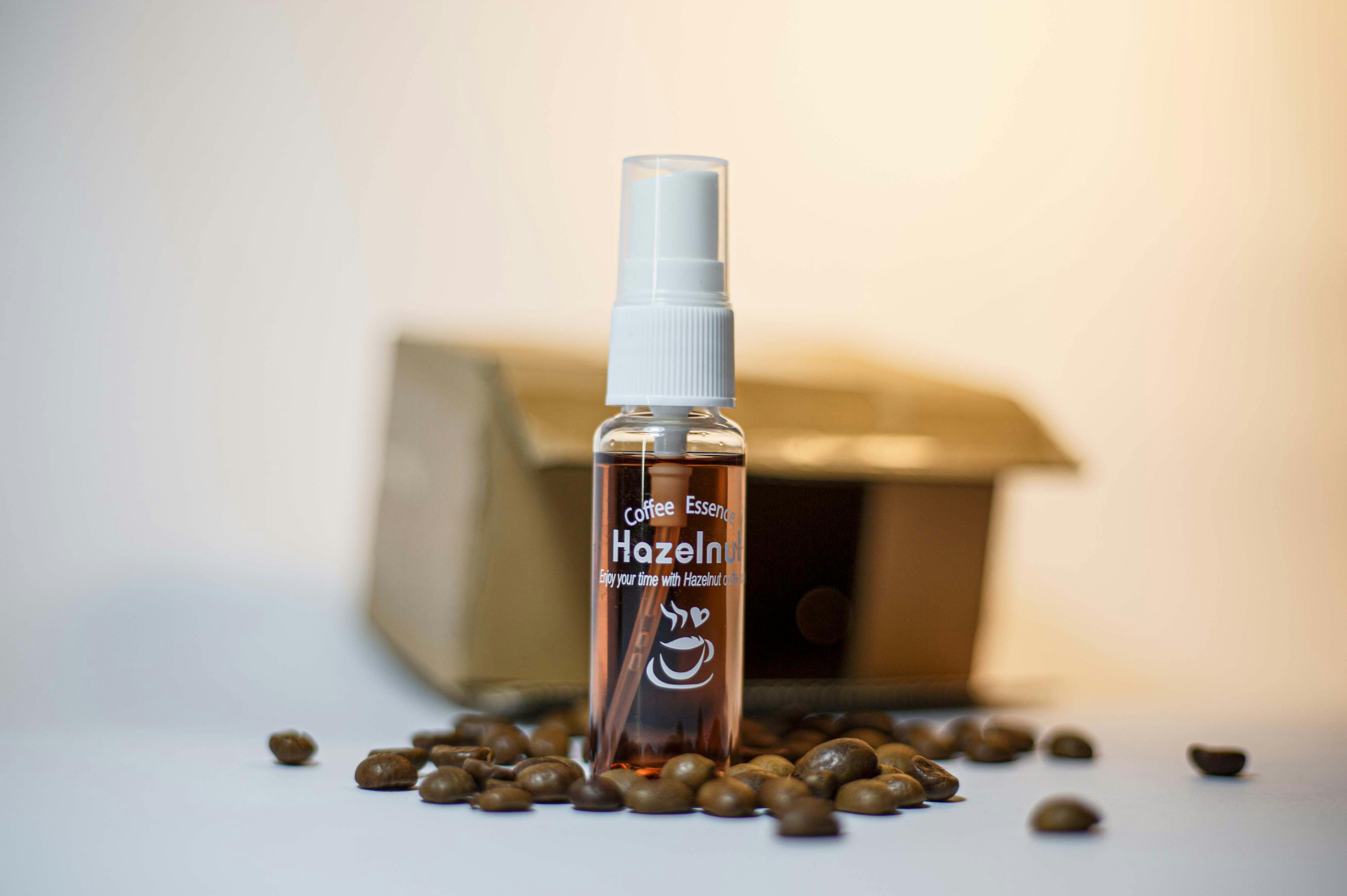 where to buy gourmet flavored coffee - A hazelnut-flavored coffee essence bottle surrounded by coffee beans, ideal for breakfast aromas.