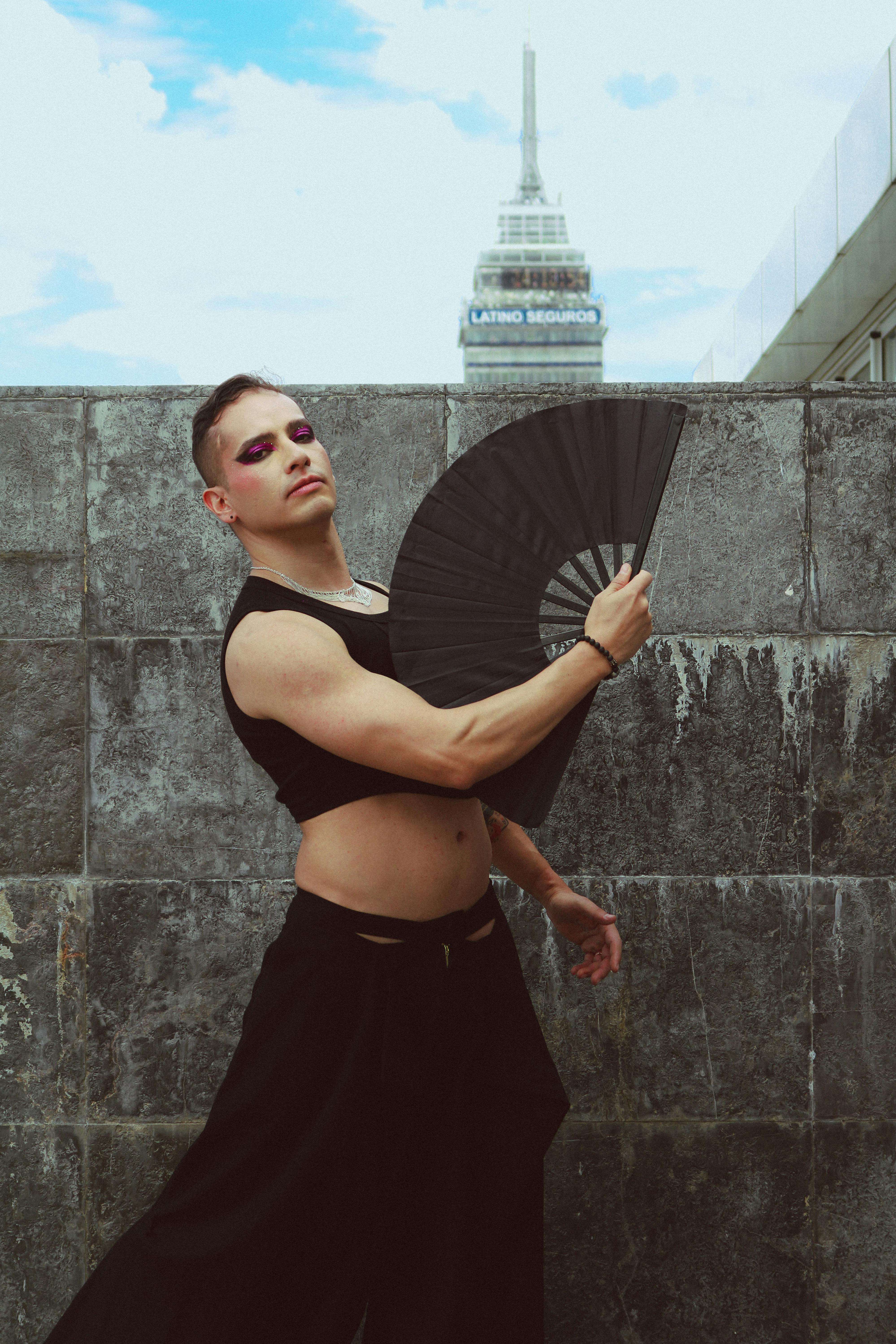 Artistic fashion portrait of a model with fan, set against a city skyscraper background.