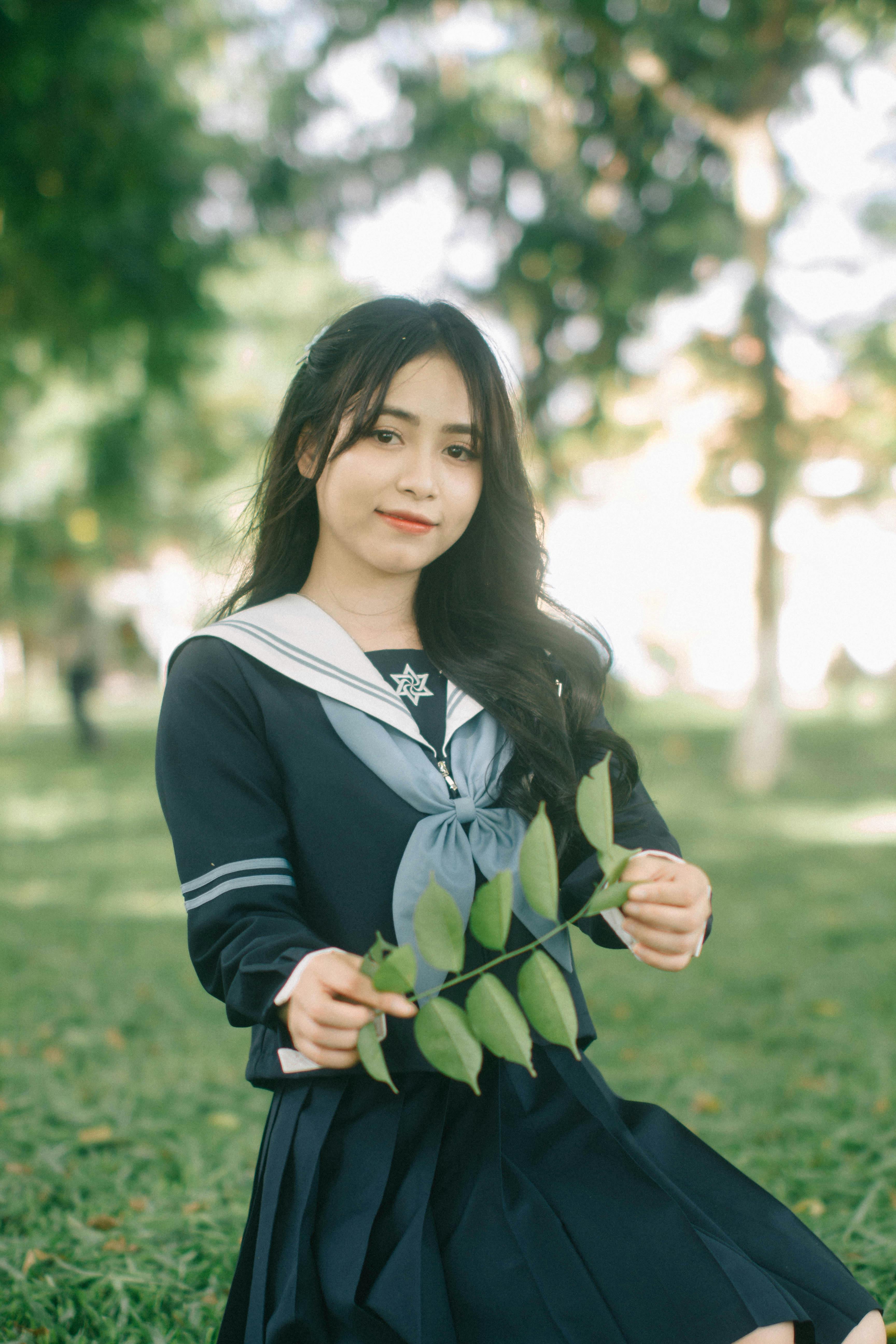 a girl in a school uniform sitting on the grass