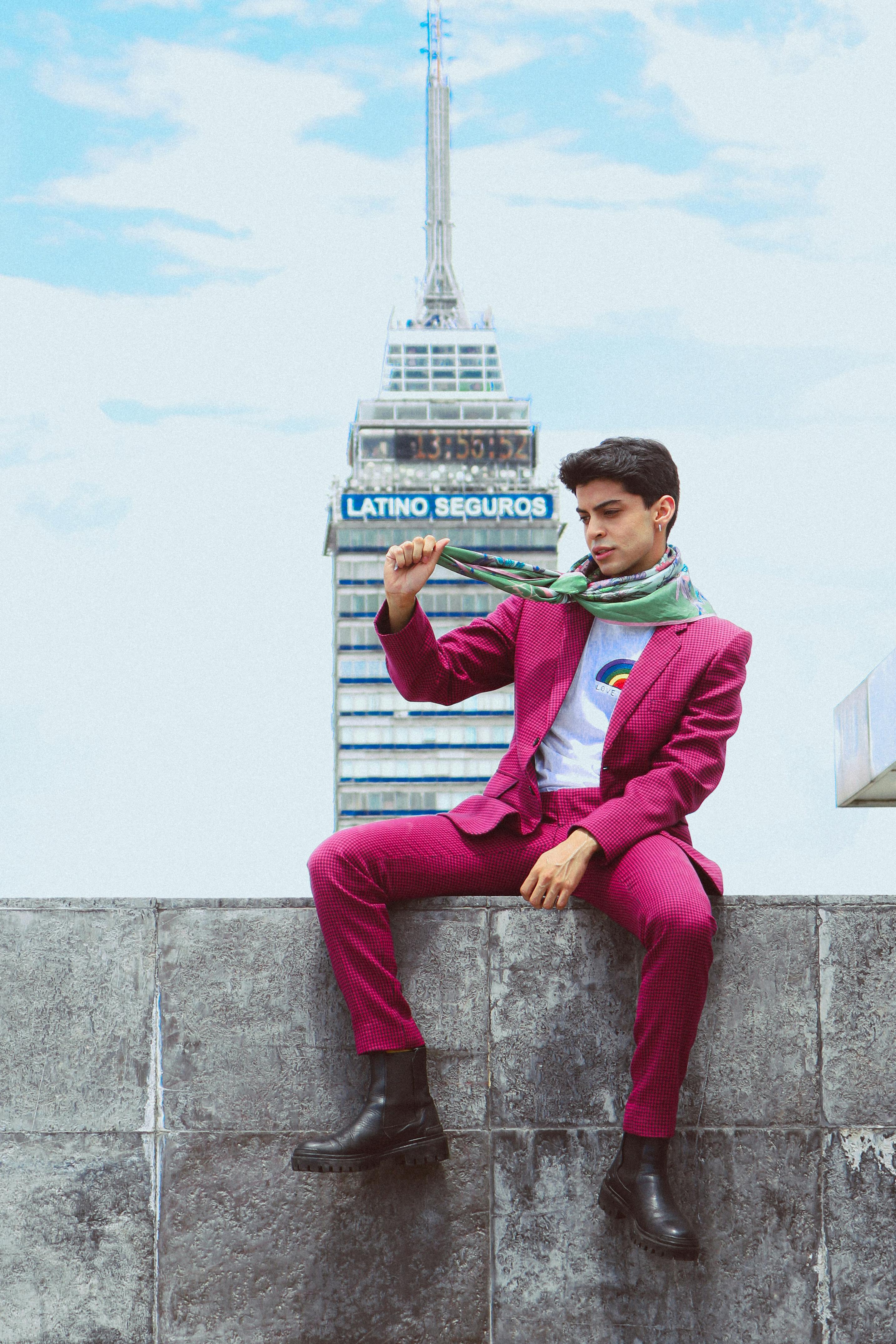 Young man in vibrant suit poses against a striking skyline, merging fashion with urban charm.