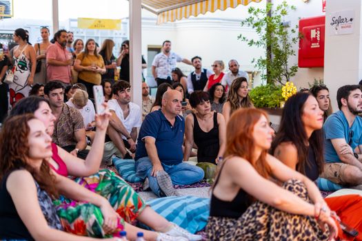 A diverse group enjoys a live music performance outdoors, capturing togetherness and cultural celebration.