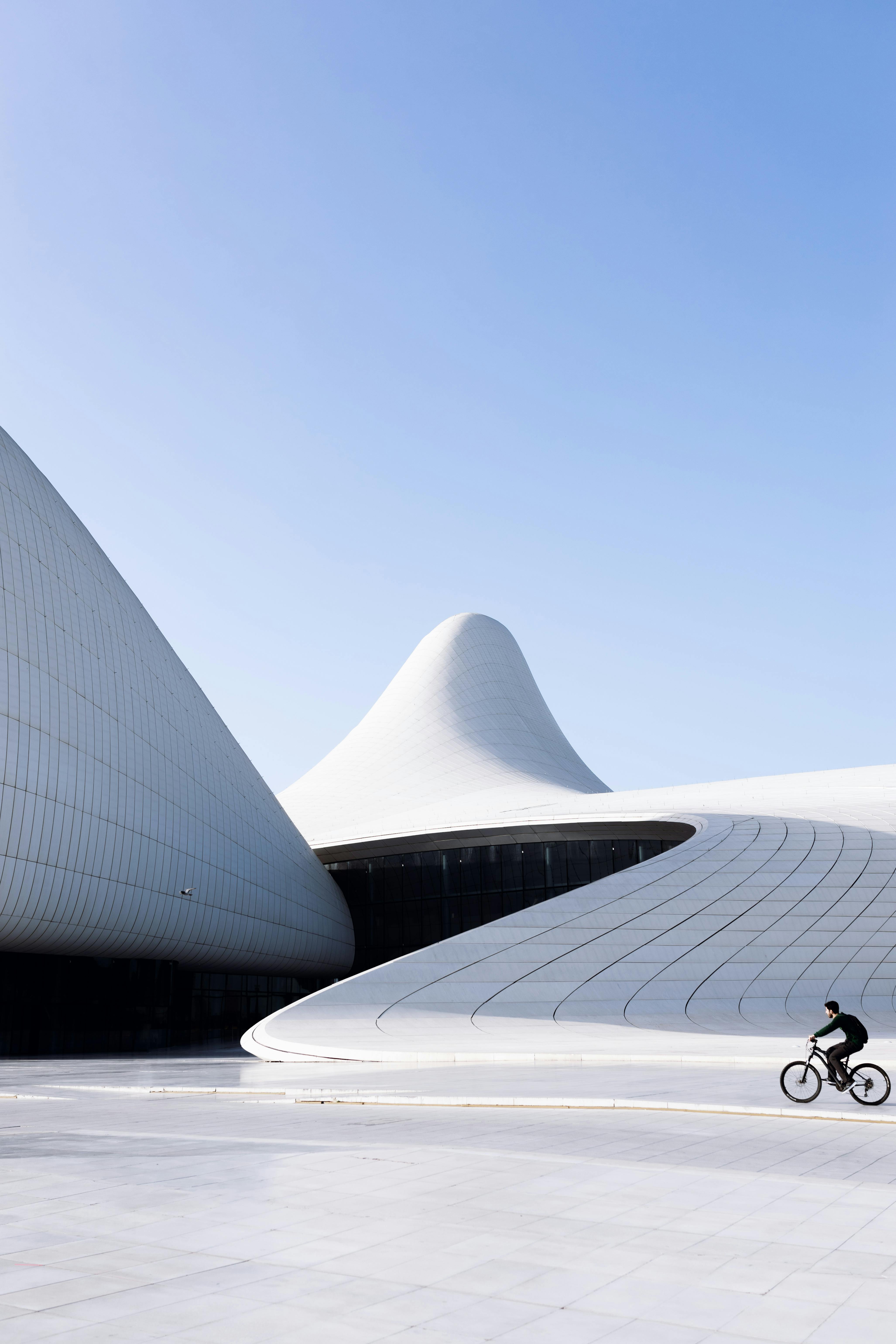 person riding bicycle in front of the heydar aliyev centre