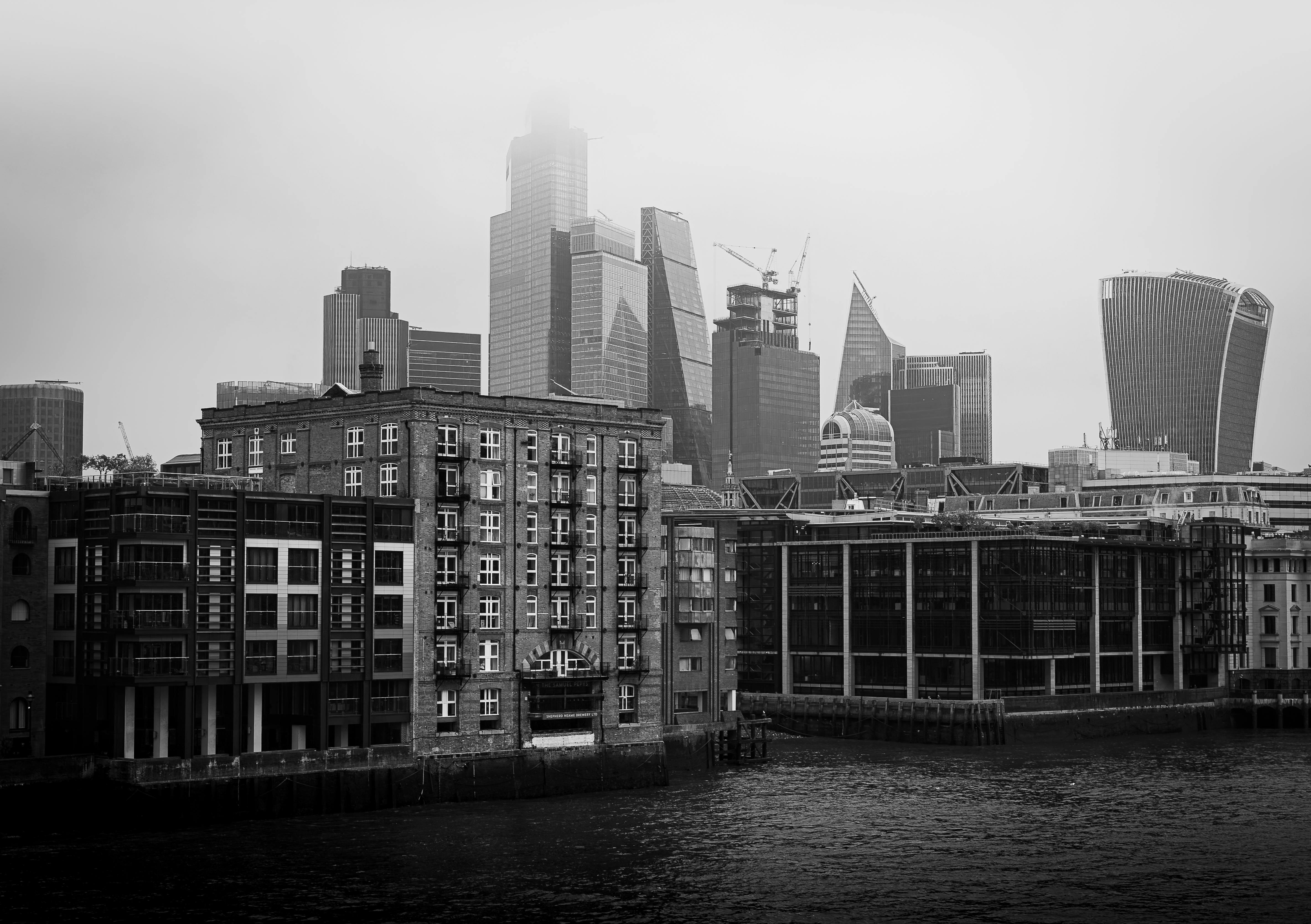Black and white cityscape of London's modern skyline with iconic skyscrapers and riverfront architecture.