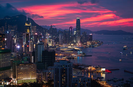 黄昏时分，灯火通明的摩天大楼坐落在宁静的海滨，构成迷人的香港城市景观