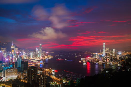 黄昏时分，从空中俯瞰香港，充满活力的天际线与港口构成一幅令人惊叹的画卷，发光的摩天大楼尽收眼底