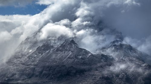 Free Majestic mountain peaks shrouded in dramatic clouds and mist, creating a mysterious and stunning natural scene. Stock Photo