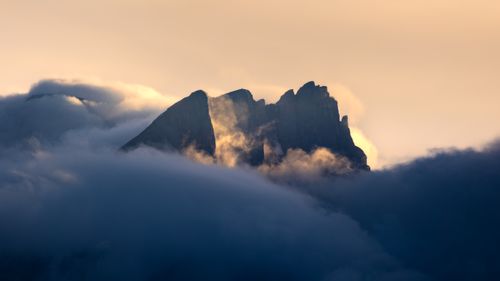 Free A dramatic mountain peak emerging through clouds during a serene dusk creating a mystical landscape. Stock Photo