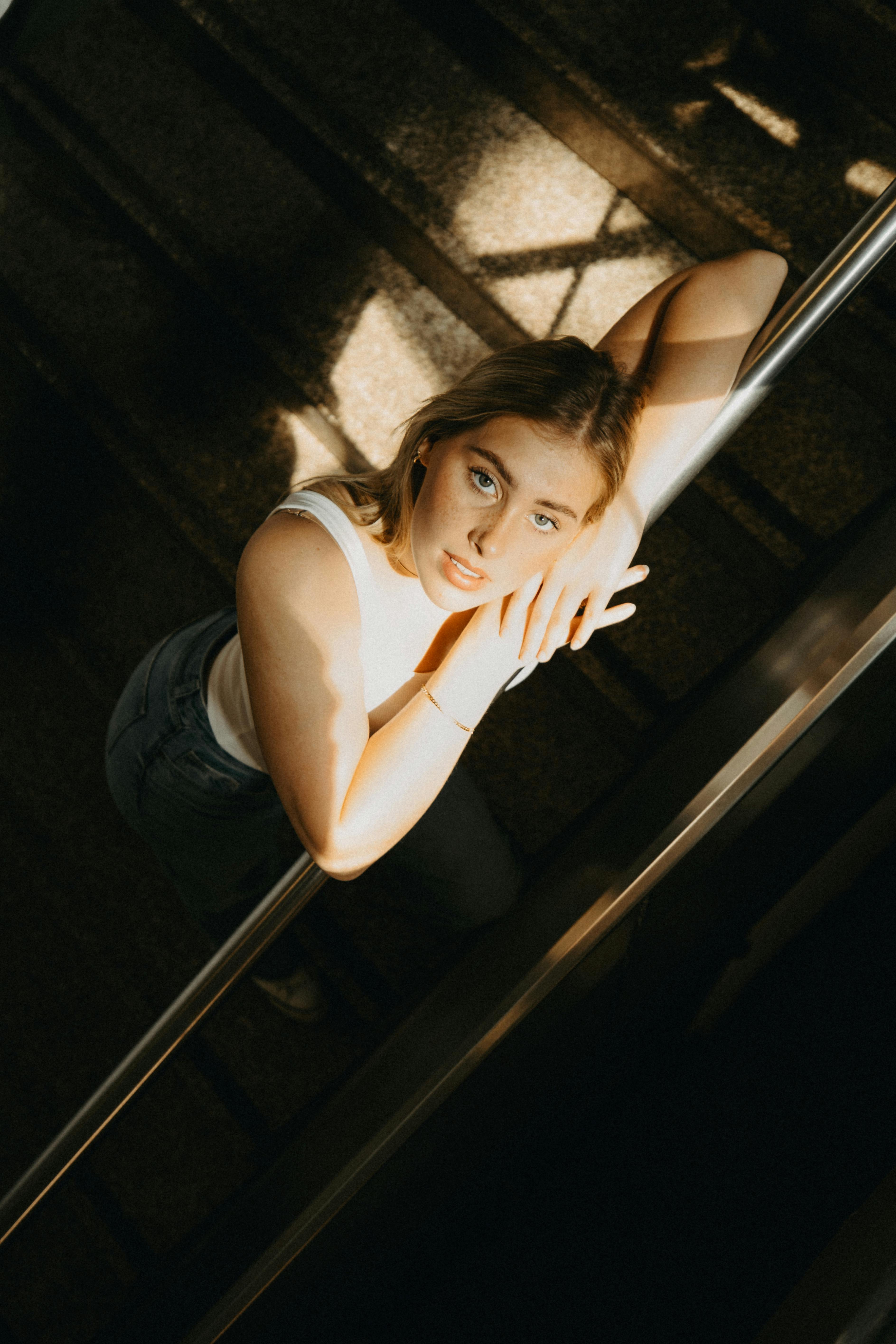 Artistic top view portrait of a young woman on stairs with dramatic lighting, perfect for modern lifestyle content.