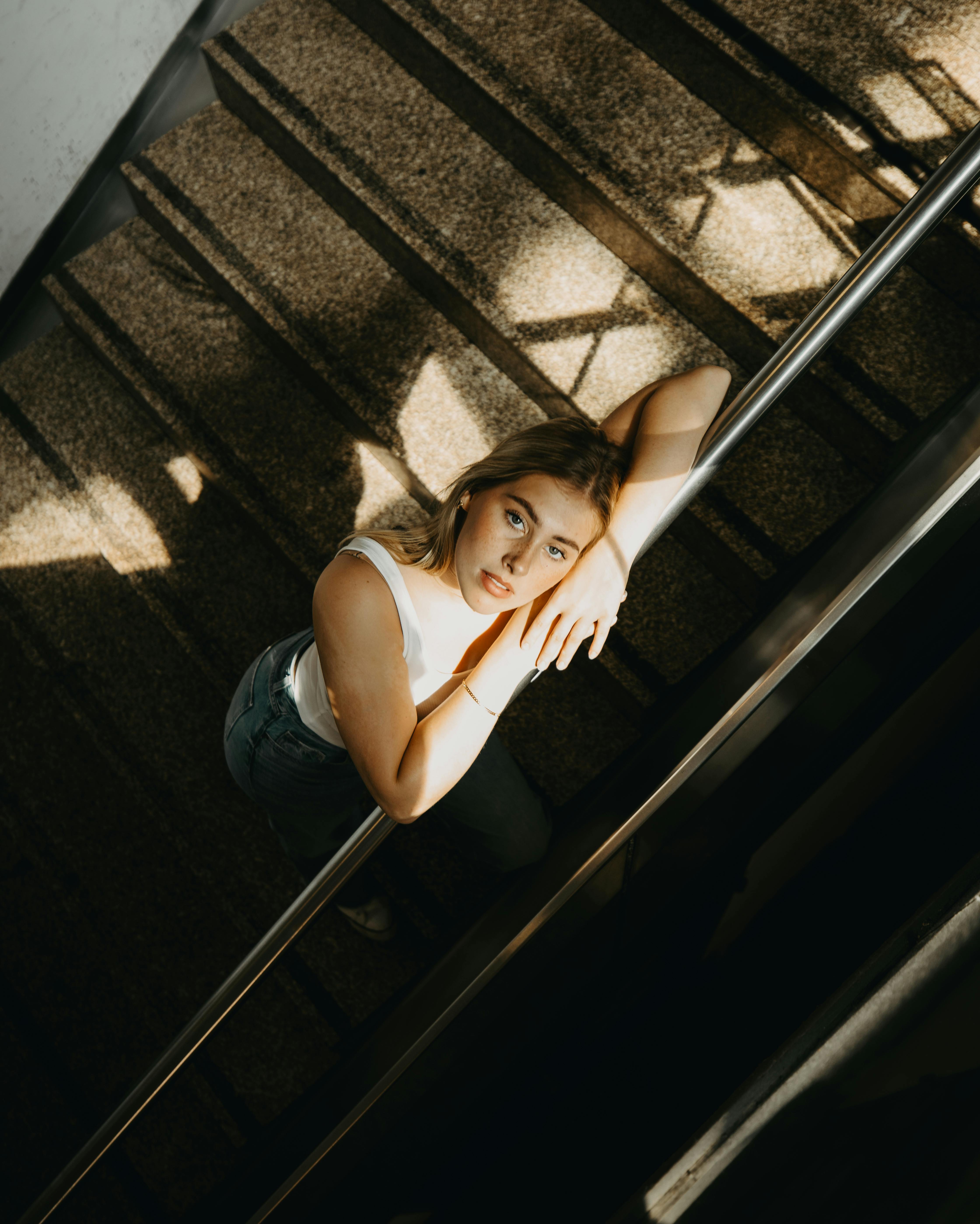 Stylish woman posing on a staircase with dramatic lighting and shadows.