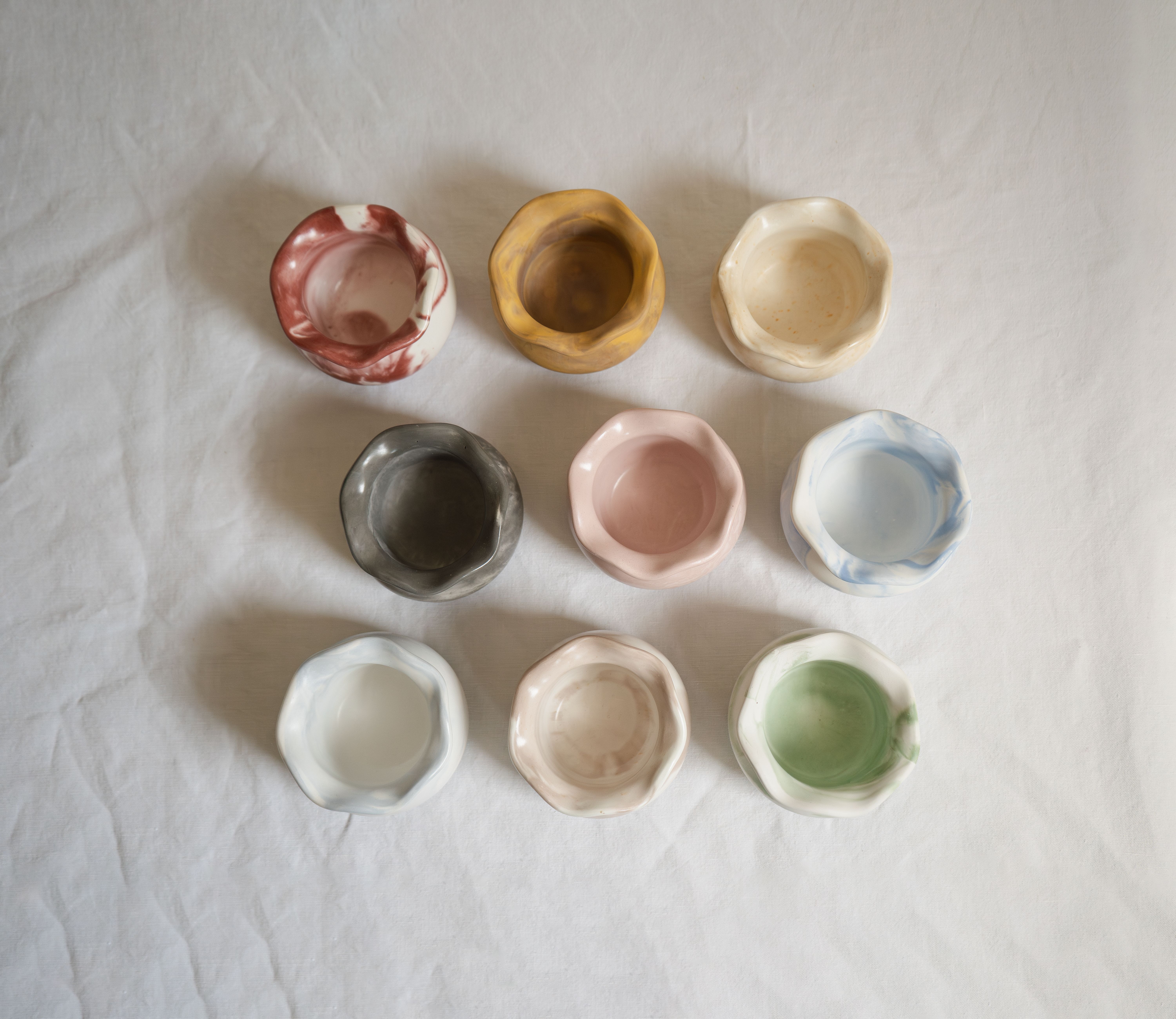 A collection of colorful ceramic bowls arranged on a white textured surface.
