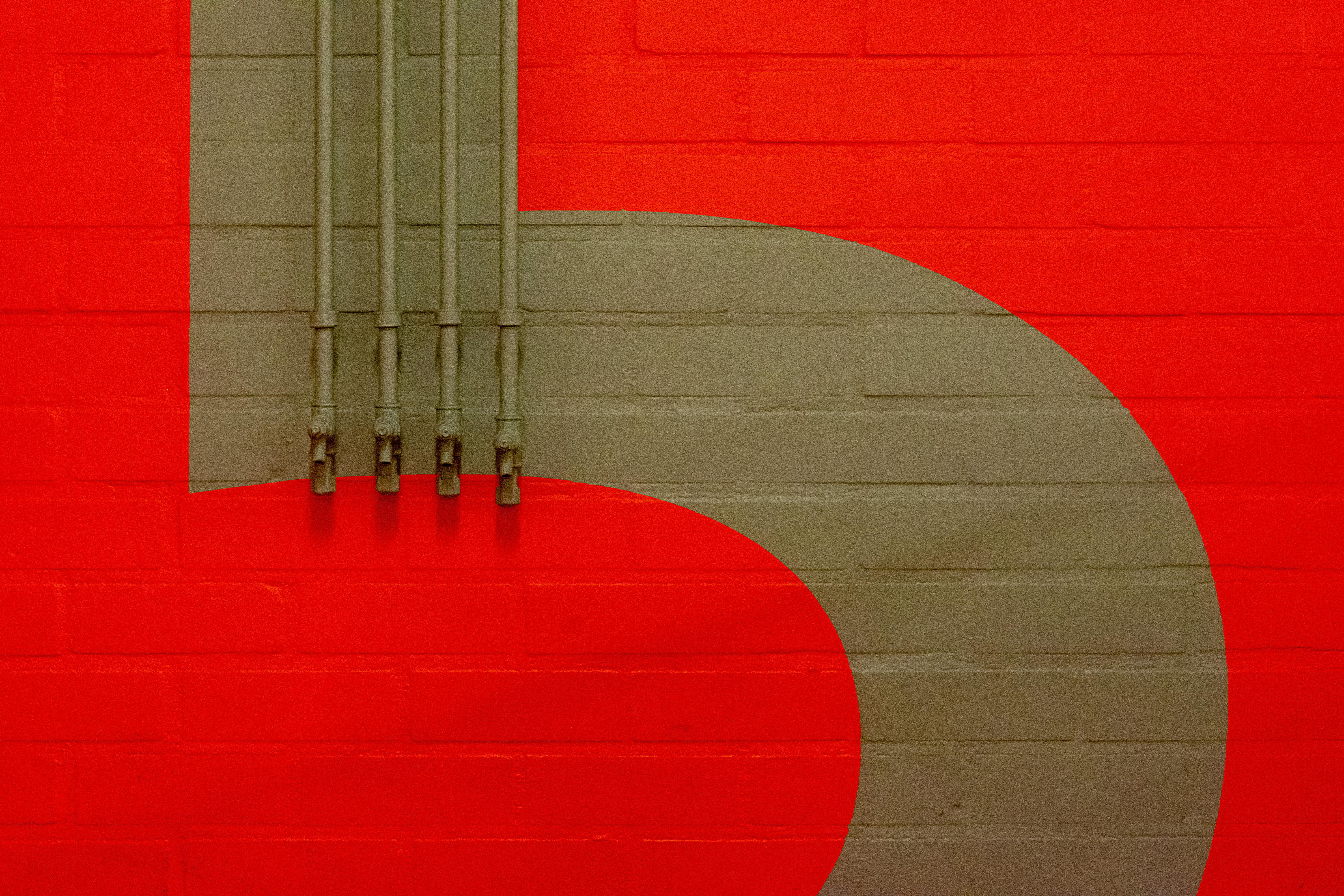 A striking industrial wall design featuring red and beige brick with metal pipes.