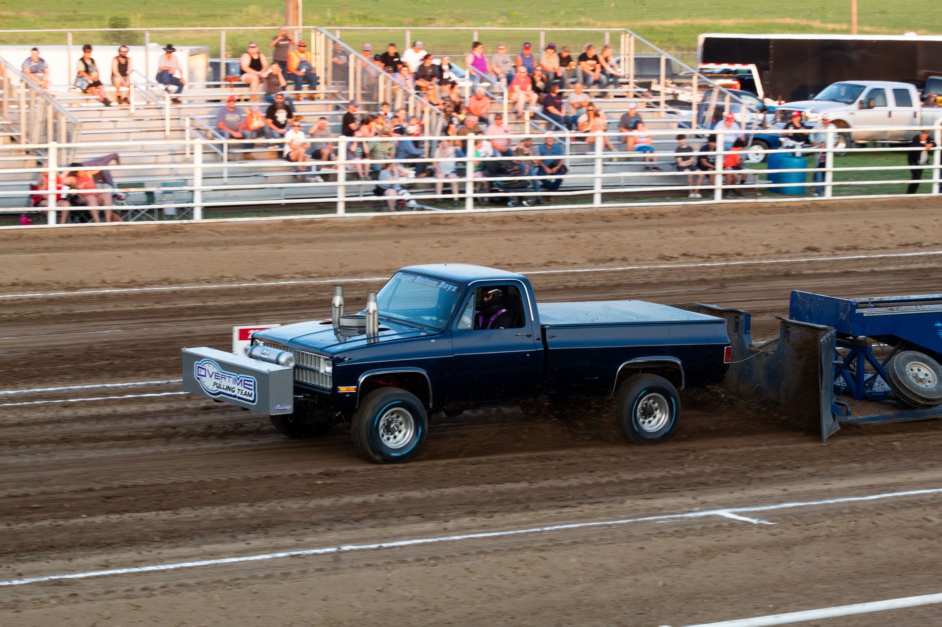 A high-energy truck pull competition capturing the thrill and excitement of motorsport at a fairground arena.
