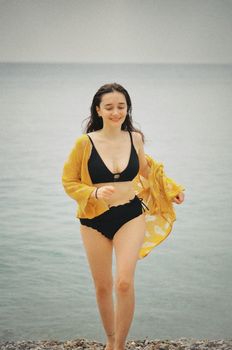 A smiling woman in a bikini and shawl enjoying a summer day at Antalya beach, Türkiye.