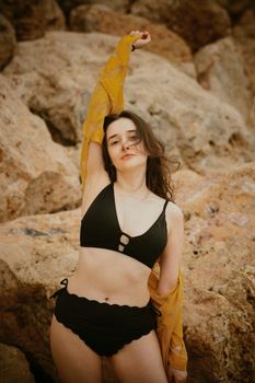 Fashionable woman in bikini posing confidently on a rocky beach in Antalya, Turkey.