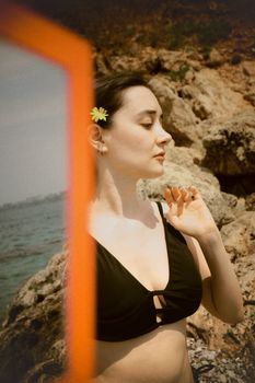 Graceful woman in a swimsuit by the rocky shore, enjoying a sunny day in Antalya.