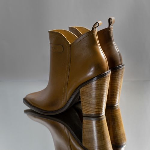 Free Stylish brown leather heeled ankle boots on reflective surface, showcasing fashion elegance. Stock Photo