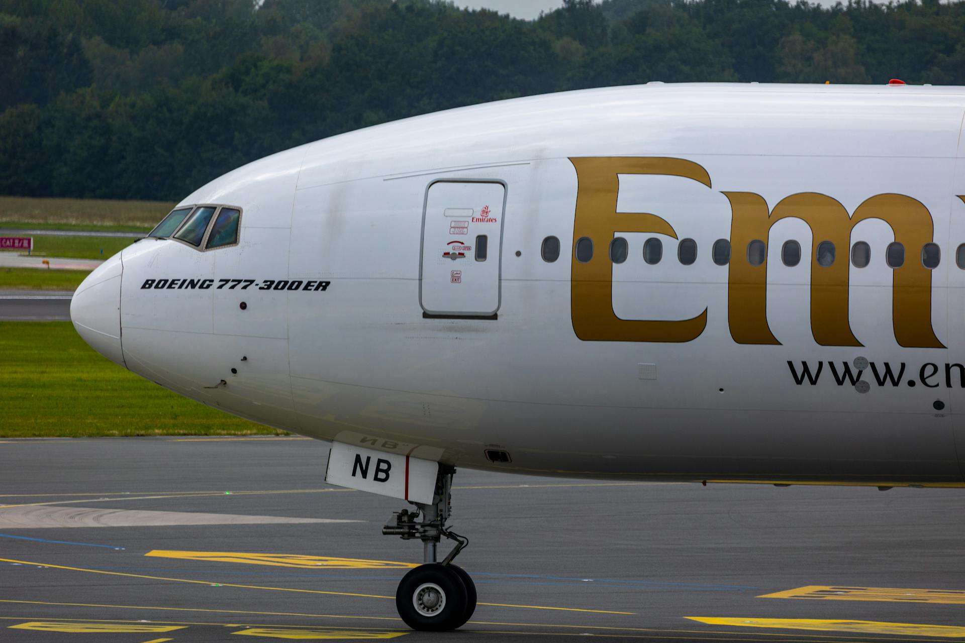 A detailed view of an Emirates Boeing 777-300ER aircraft on the runway, showcasing its front side.