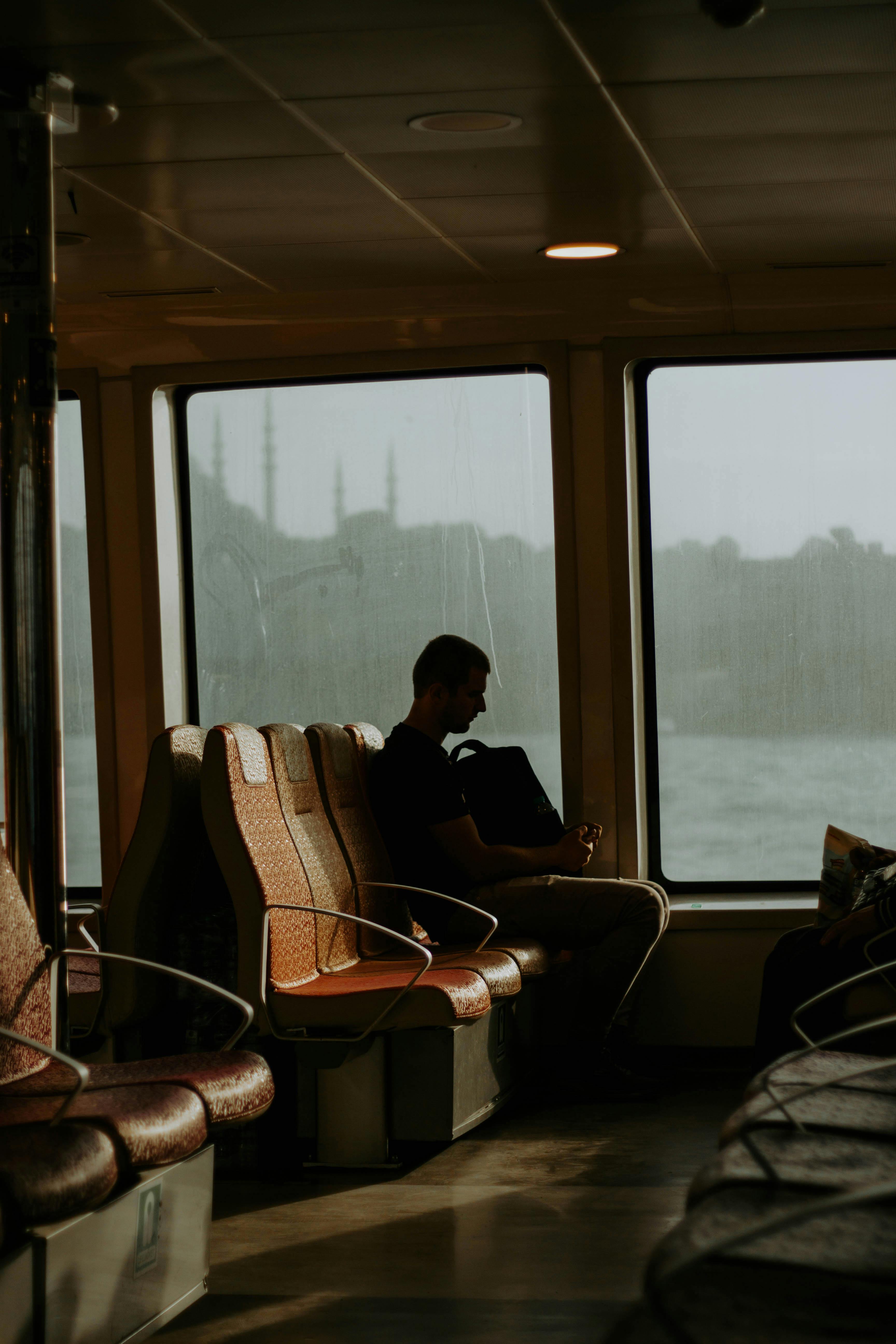 A solitary man sits on a ferry in Istanbul at sunset, reflecting in the warm light.