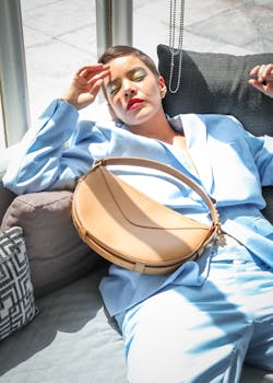 A fashionable woman in a blue suit relaxes indoors, showcasing modern style and elegance.