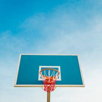 A vibrant basketball hoop and backboard contrast with the clear blue sky, perfect for sports backgrounds.