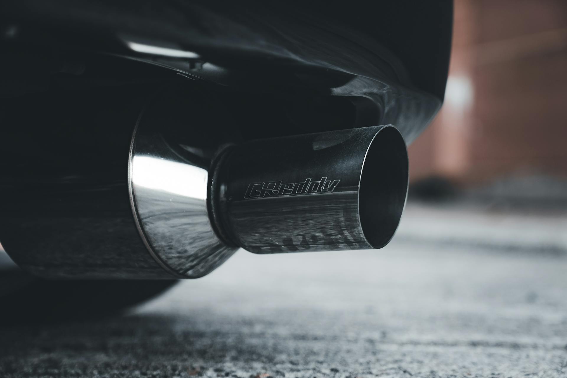 Detailed shot of a car exhaust pipe with condensation, highlighting chrome and steel features.