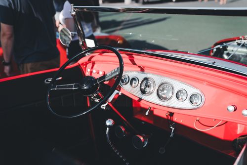 Free Close-up view of a classic red convertible dashboard featuring a vintage steering wheel and chrome details at a car show. Stock Photo
