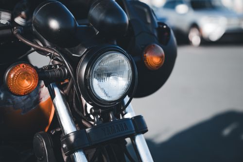 Free Detailed view of a classic motorcycle headlight with chrome features outdoors. Stock Photo