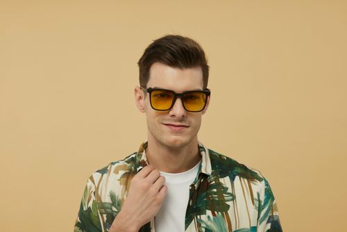 Free Young man in tropical shirt with sunglasses on a neutral background showcasing modern fashion. Stock Photo