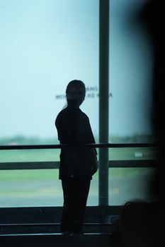 Moody silhouette of a person standing by a window at Surabaya airport, East Java, Indonesia.