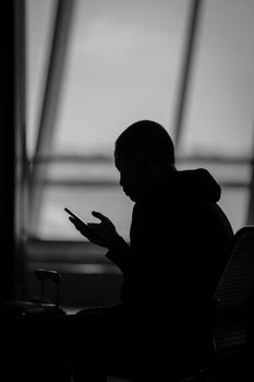Silhouette of a man using a smartphone in an airport terminal in Surabaya, Indonesia.