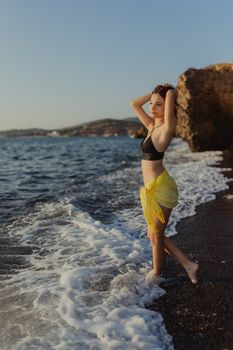 Woman in swimwear relaxing on a scenic beach during sunset, embodying summer leisure and travel vibes.