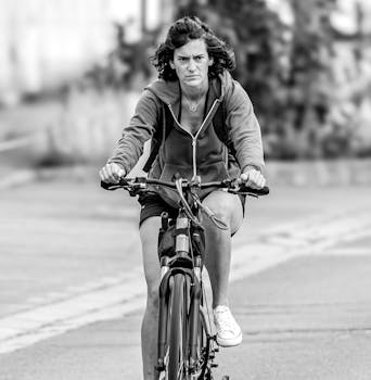 Determined woman cycling on a city road in black and white, emphasizing outdoor exercise.