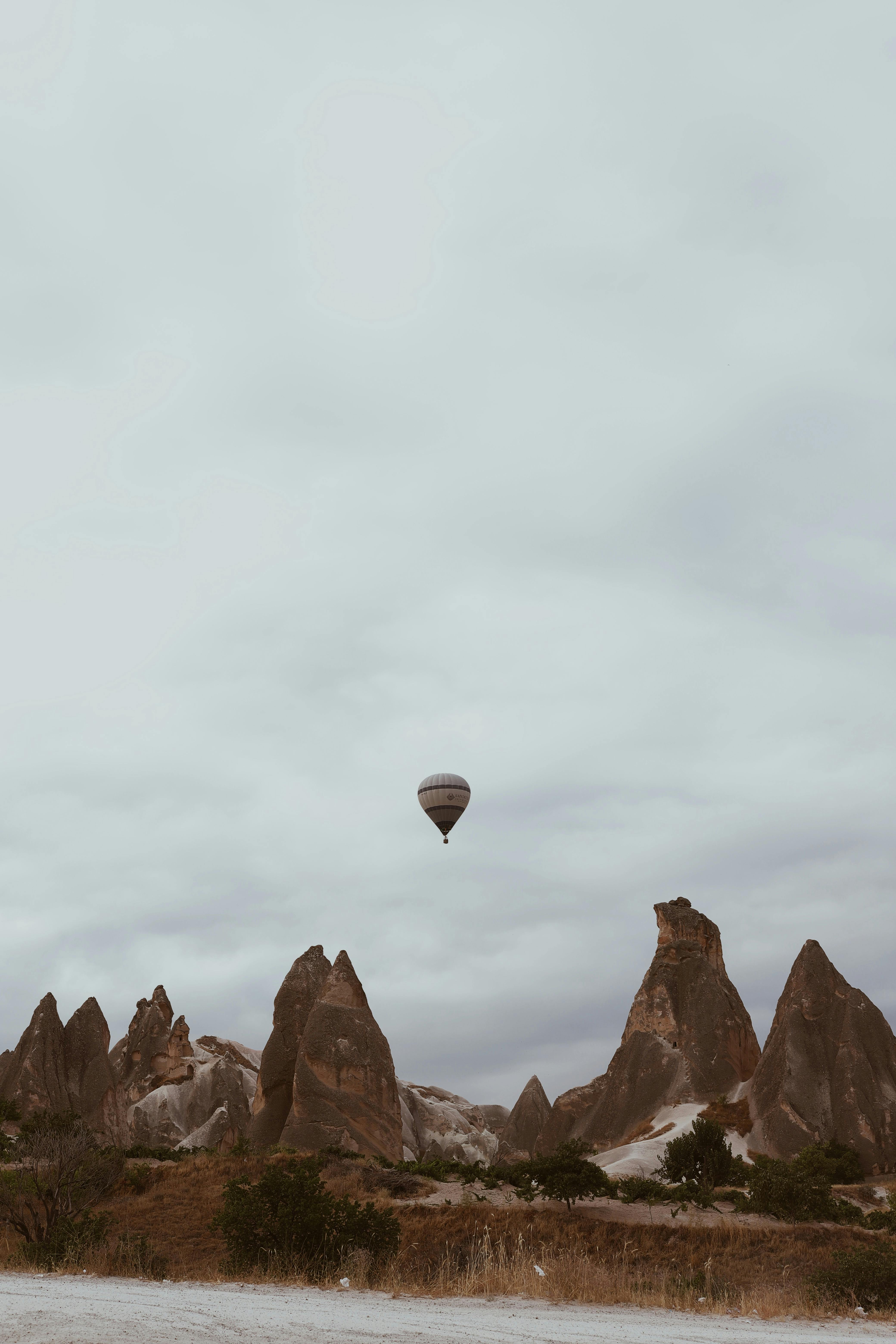 A serene hot air balloon flight over Cappadocia's iconic rock formations under a cloudy sky.