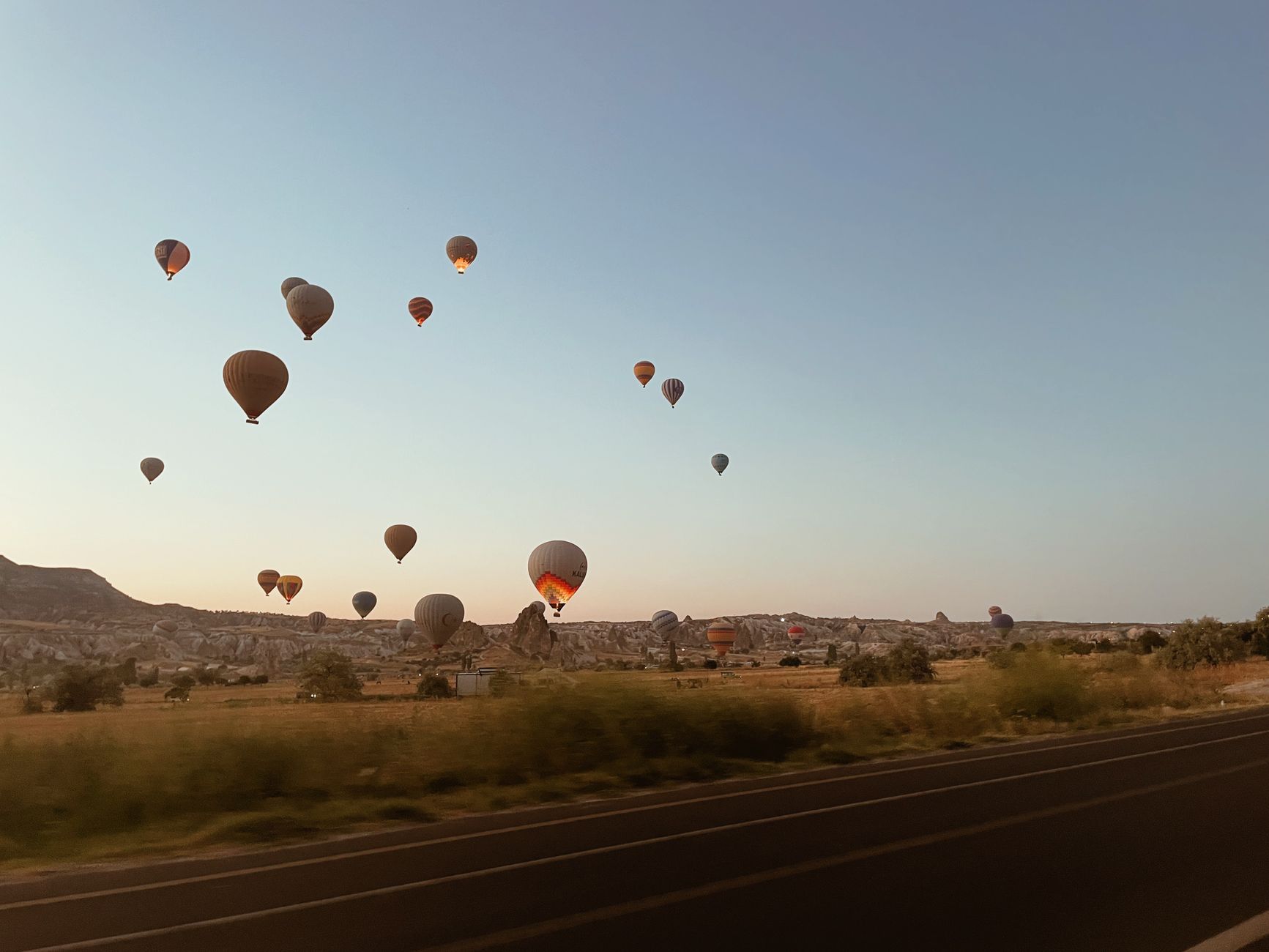 Scenic view of hot air balloons floating over the Cappadocia landscape at sunrise in Türkiye. — photo by Hatice / Pexels