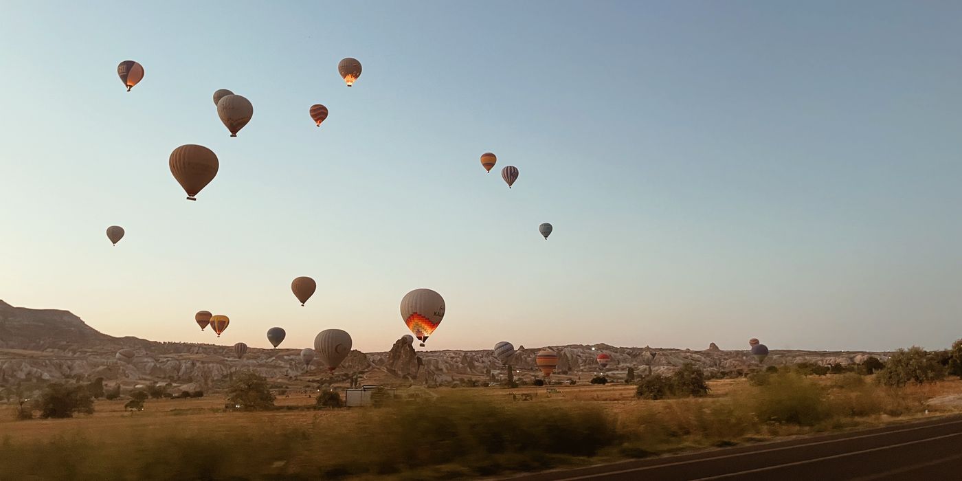 Hot air balloons rising over the Cappadocia valley at sunrise in Turkiye
