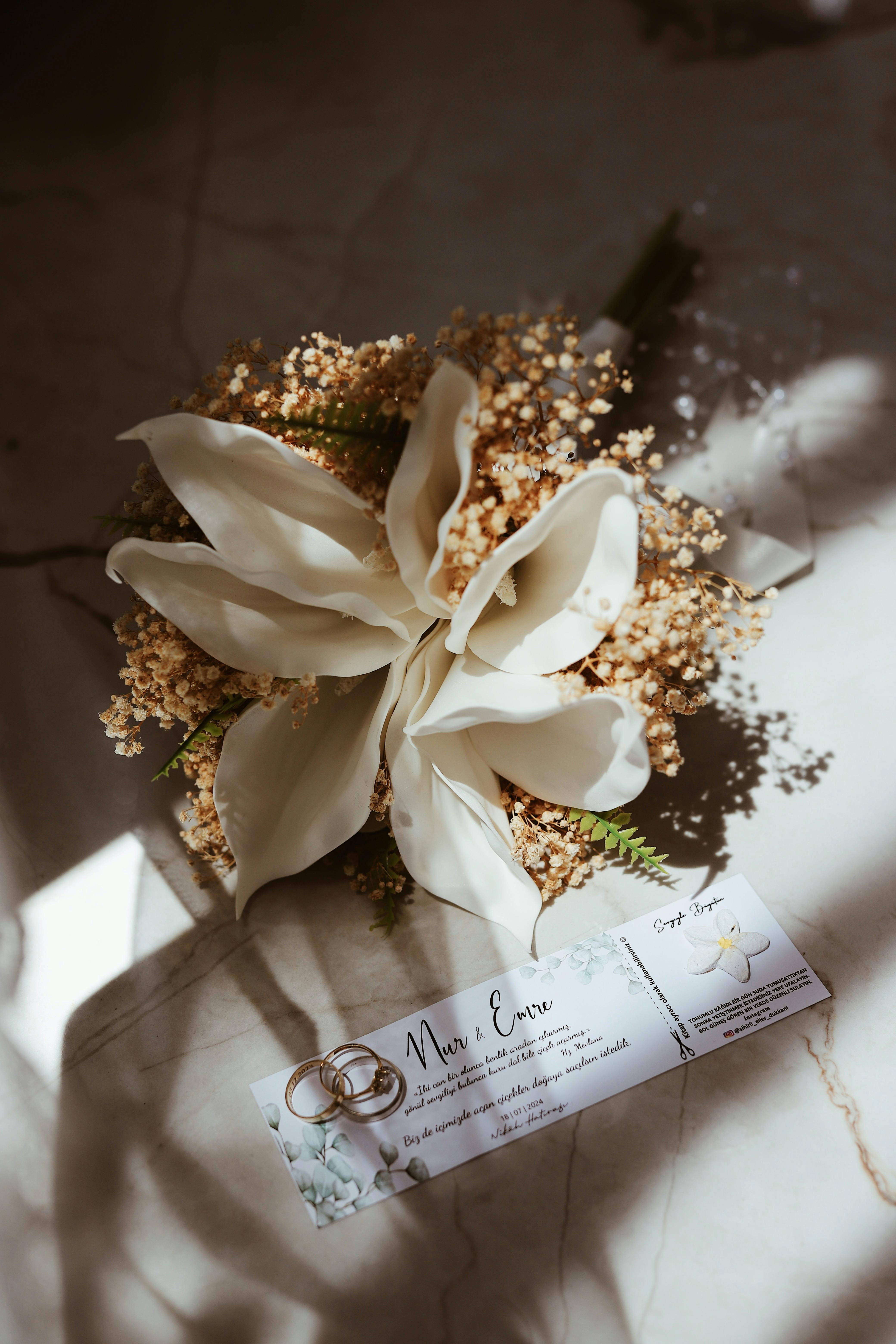 Beautiful wedding bouquet with a vintage invitation card on a marble surface.