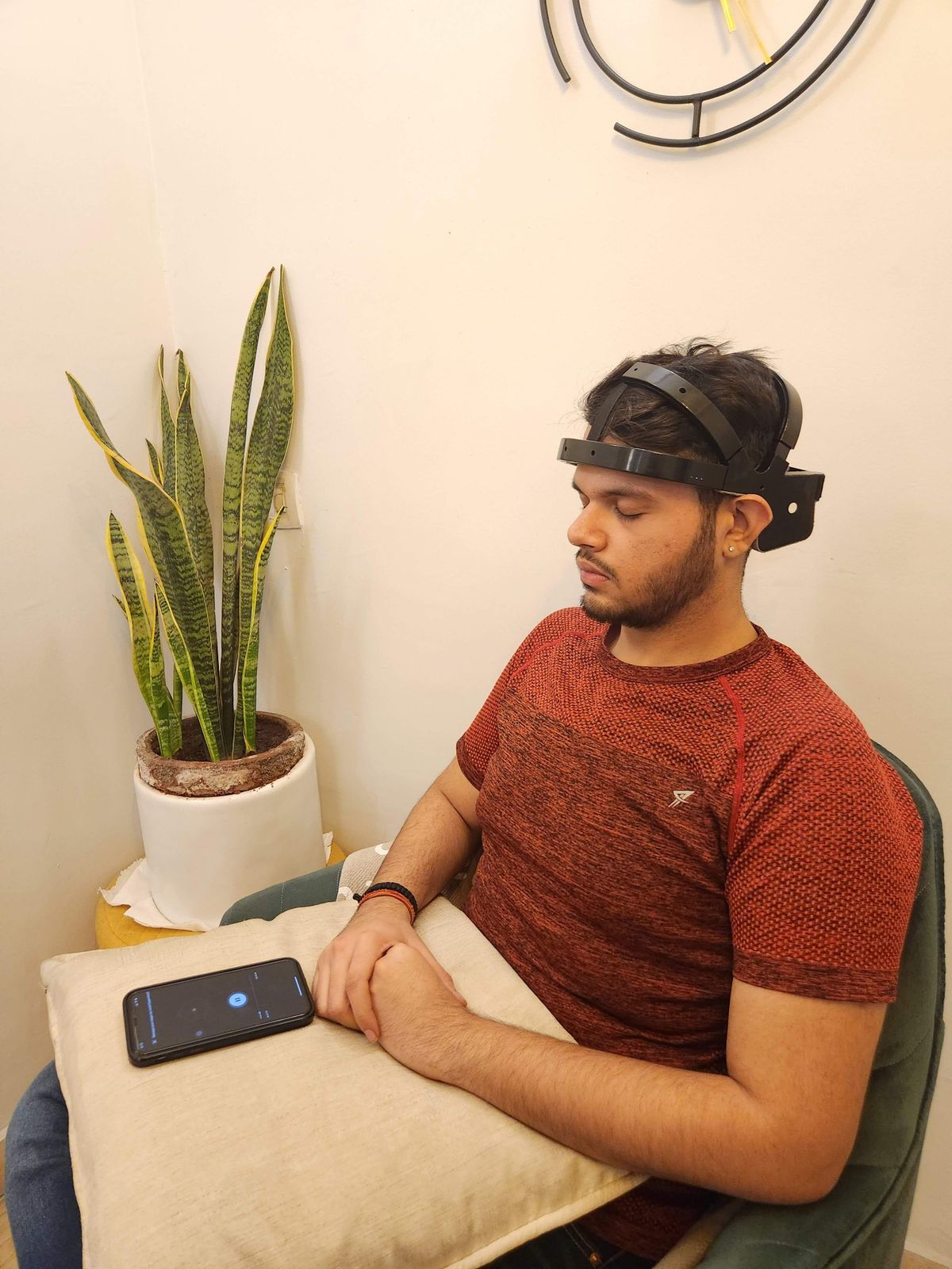 A person seated in a quiet room wearing a wireless EEG headband during a training session.