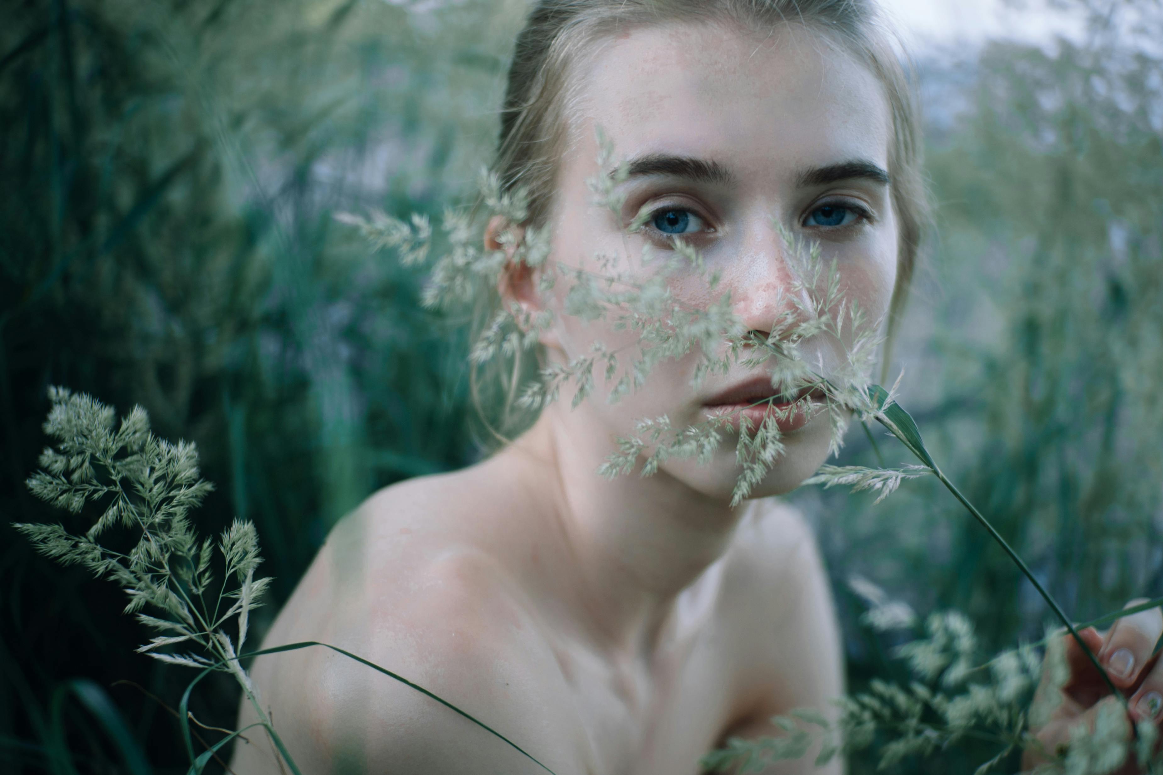 woman s face behind green plant