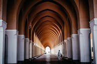 走廊令人惊叹，拱形天花板和温暖的色调中，有一个人在行走