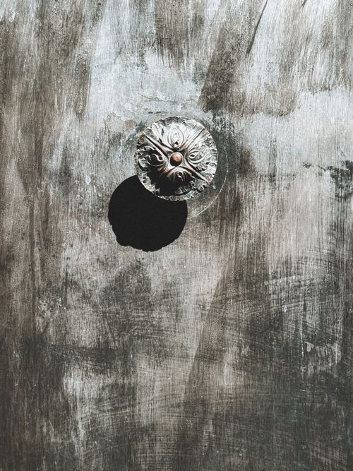 Free A vintage metal knob casting a shadow on a weathered wooden wall, exuding a rustic and antique charm. Stock Photo