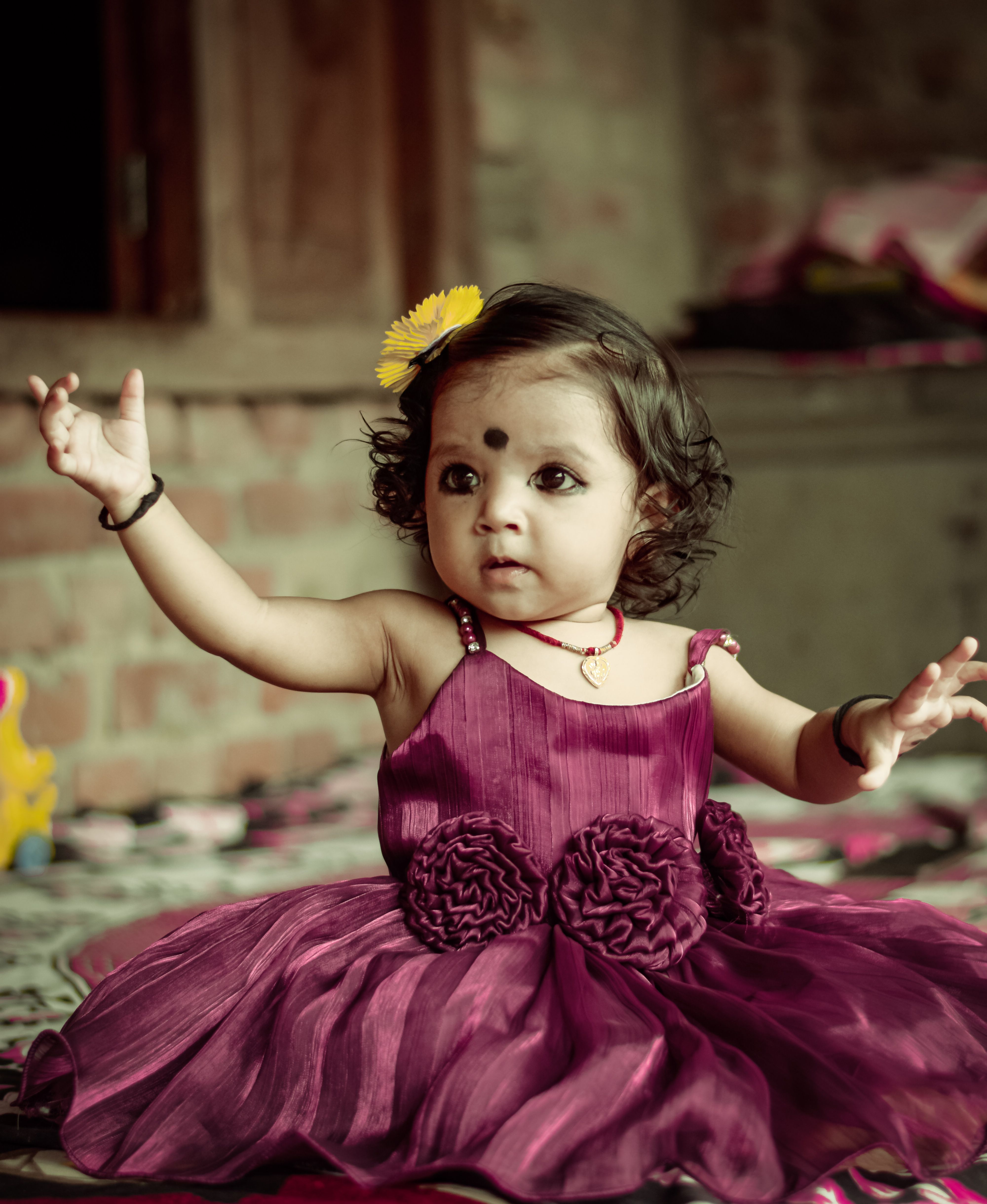 A little girl in a purple dress is holding her hands up · Free Stock Photo