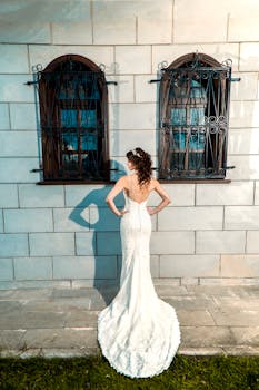 新娘照片中，一名身穿白色礼服的女子靠在石墙上