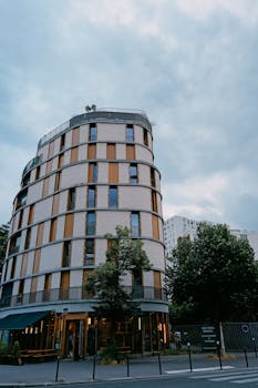 Stylish contemporary urban building with unique curves and glass elements under a cloudy sky.