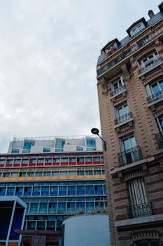 Photo by Adrien Olichon Vibrant city buildings showcasing modern urban architecture with colorful facade and classic elements.
